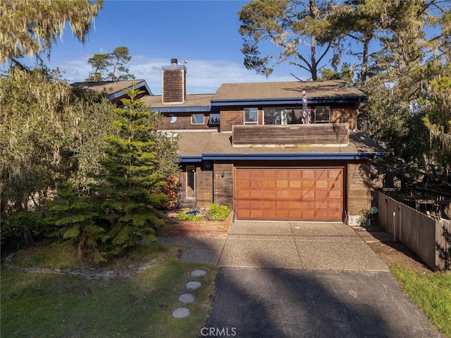 view of front of property featuring an attached garage, a chimney, fence, and concrete driveway