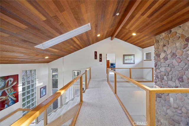 hall featuring lofted ceiling with skylight, wooden ceiling, an upstairs landing, and light colored carpet