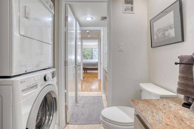 clothes washing area featuring stacked washer and clothes dryer and light tile patterned flooring