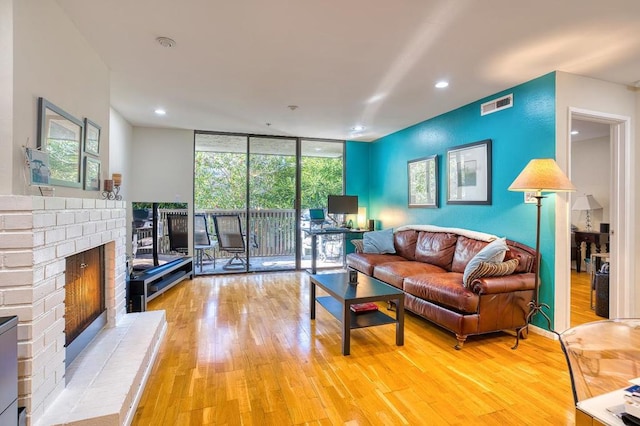 living room featuring a fireplace, light hardwood / wood-style flooring, and floor to ceiling windows