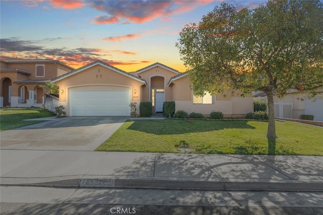 mediterranean / spanish home with a garage, driveway, a front yard, and stucco siding