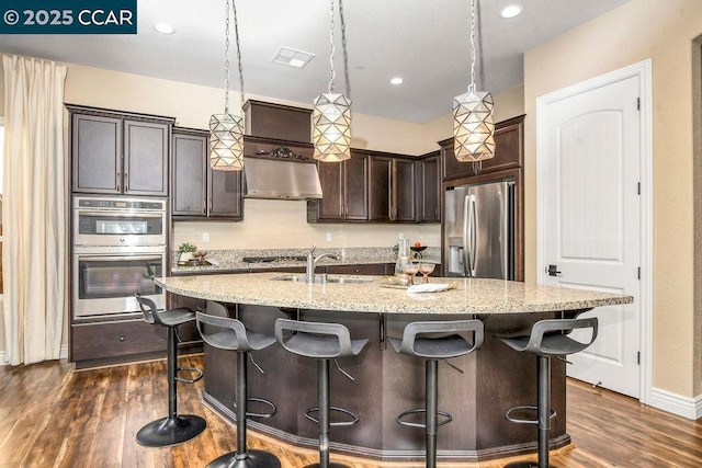 kitchen with sink, extractor fan, a center island with sink, appliances with stainless steel finishes, and pendant lighting