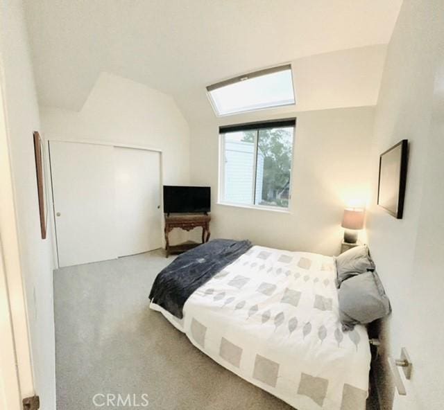 bedroom with light colored carpet, lofted ceiling, and a closet