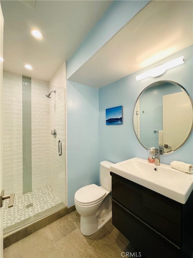 bathroom featuring toilet, vanity, and a shower with shower door