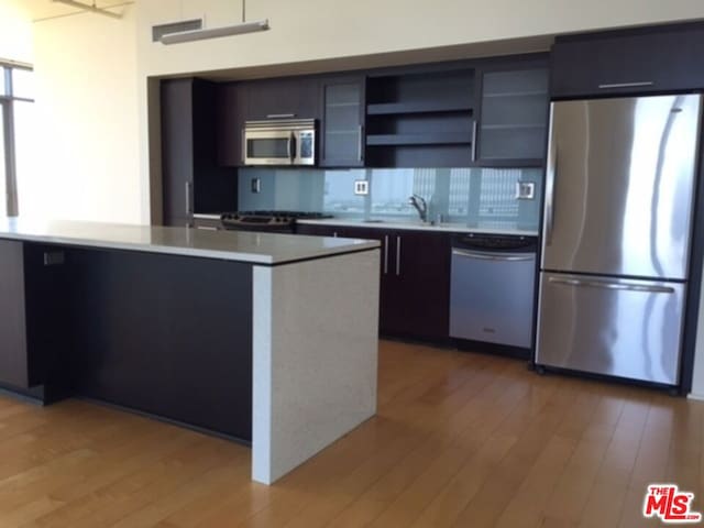 kitchen featuring stainless steel appliances, a kitchen island, sink, and hardwood / wood-style floors