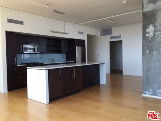 kitchen featuring tasteful backsplash, dark brown cabinetry, stainless steel appliances, and a center island