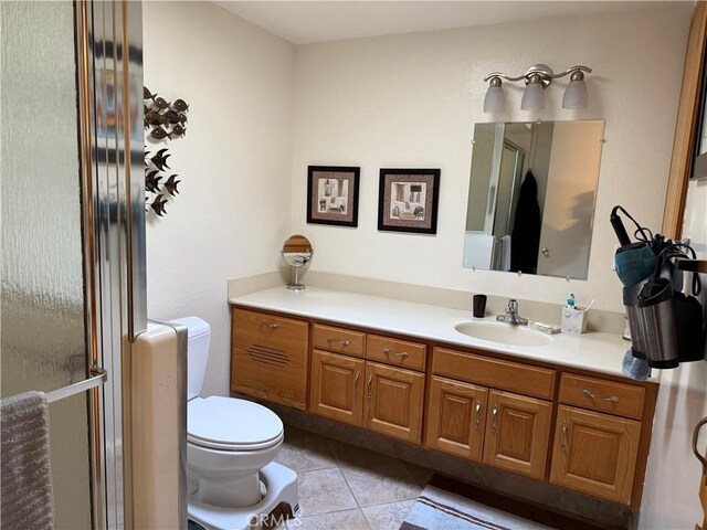 bathroom with tile patterned flooring, vanity, a shower with shower door, and toilet