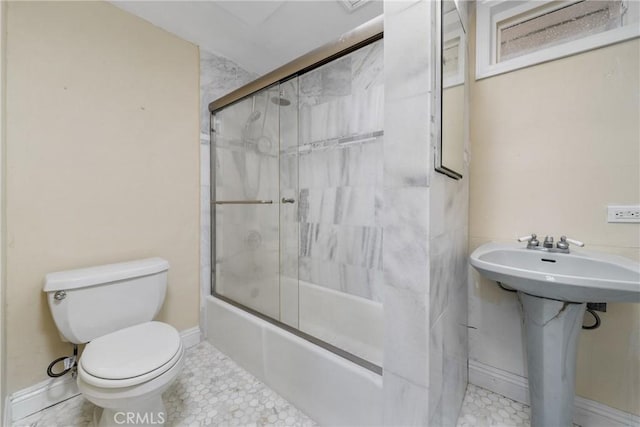 full bathroom featuring sink, bath / shower combo with glass door, tile patterned floors, and toilet