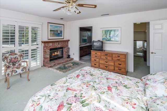 bedroom featuring ensuite bathroom, light carpet, a fireplace, and ceiling fan