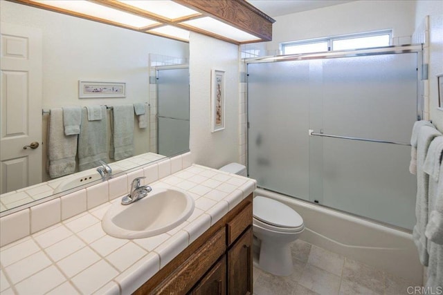 full bathroom featuring toilet, vanity, and shower / bath combination with glass door