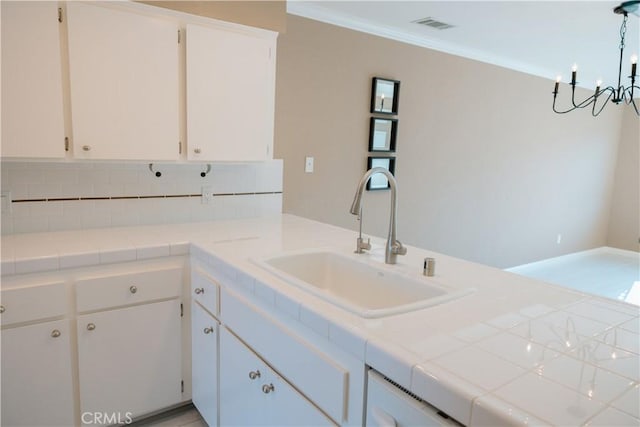 kitchen featuring pendant lighting, sink, crown molding, white cabinets, and tile countertops