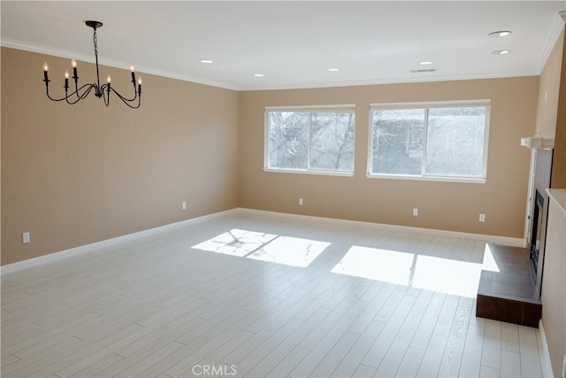 spare room featuring ornamental molding, a notable chandelier, and light wood-type flooring