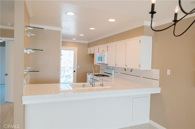 kitchen with white cabinetry, sink, ornamental molding, kitchen peninsula, and white appliances