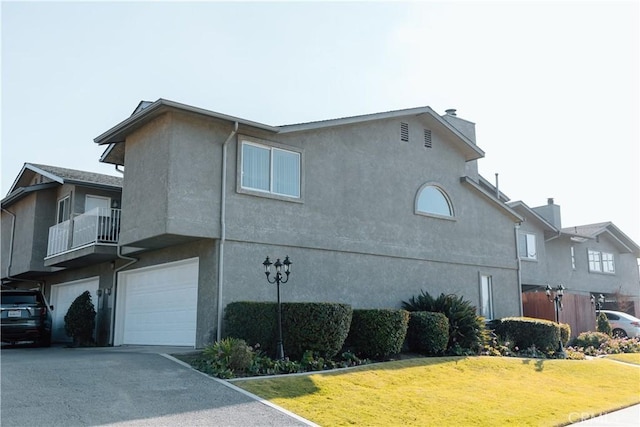 view of side of home featuring stucco siding, an attached garage, and a yard