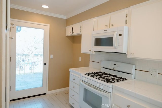 kitchen with white cabinetry, tasteful backsplash, ornamental molding, tile counters, and white appliances