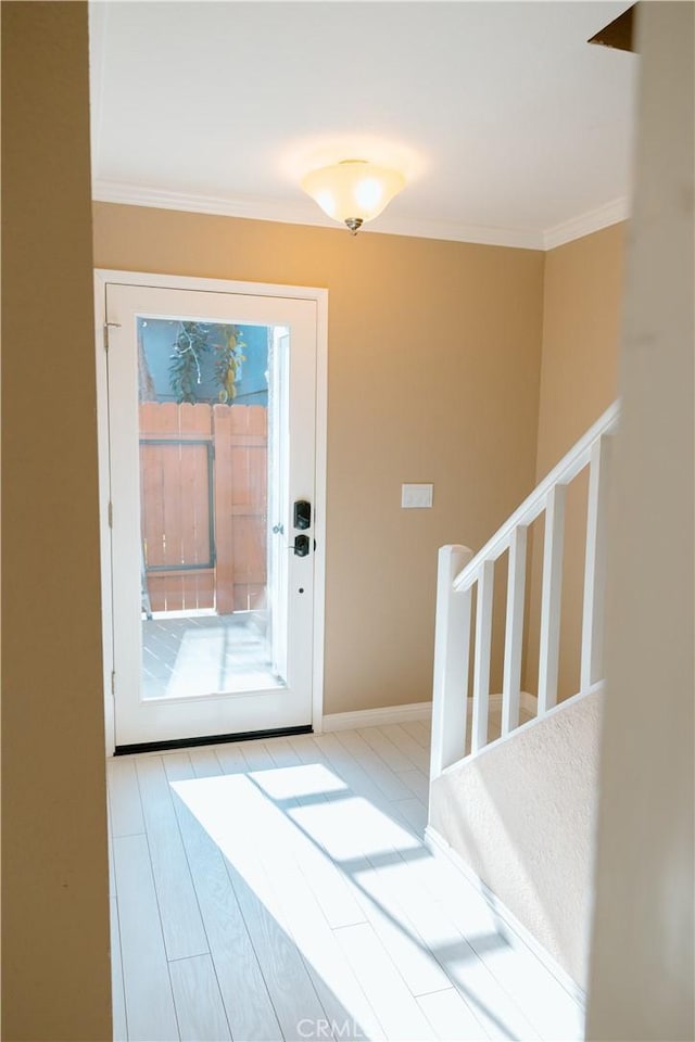 doorway with a wealth of natural light, ornamental molding, and light wood-type flooring