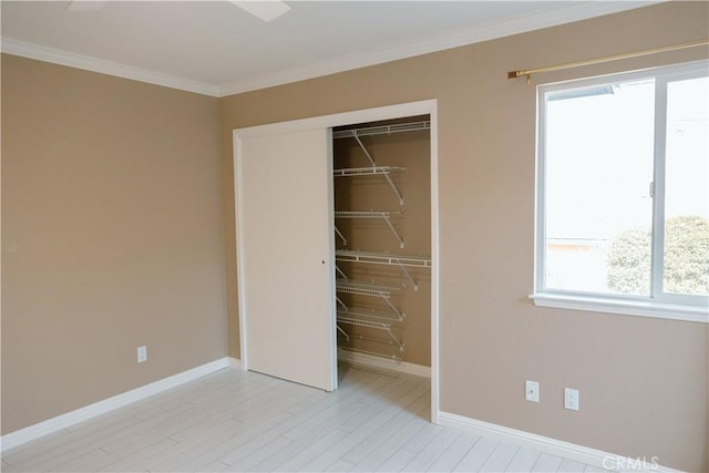 unfurnished bedroom featuring crown molding, multiple windows, a closet, and light wood-type flooring