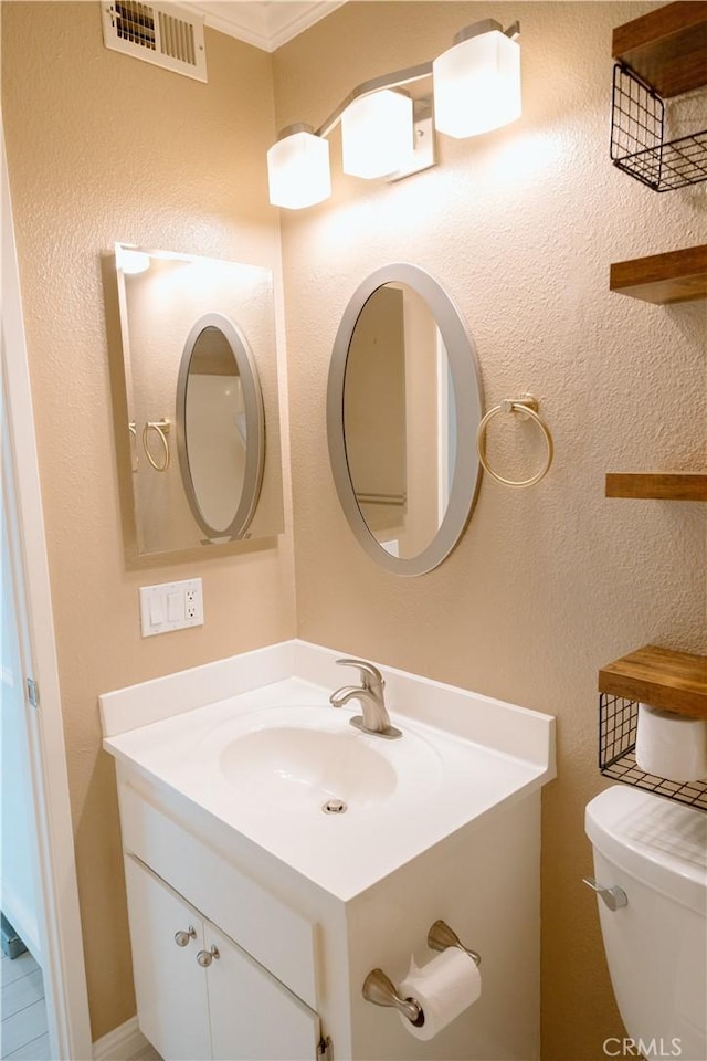 bathroom with ornamental molding, vanity, and toilet