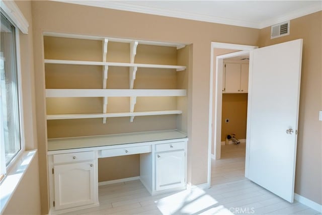 unfurnished office featuring visible vents, baseboards, built in features, built in study area, and crown molding