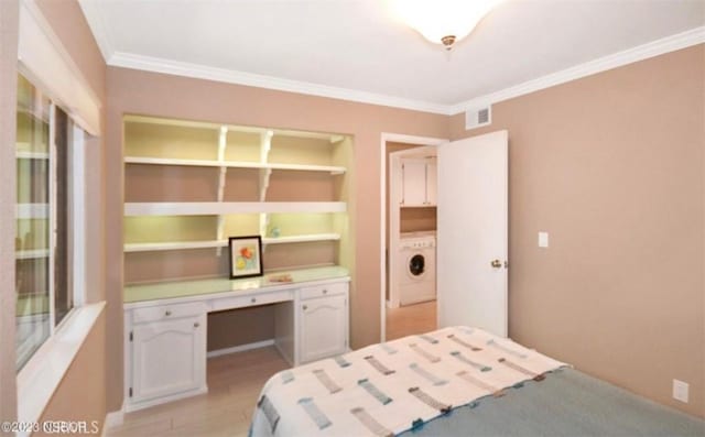 bedroom featuring crown molding, built in desk, light wood-style floors, and washer / dryer