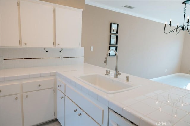 kitchen with a notable chandelier, a sink, backsplash, and white cabinetry