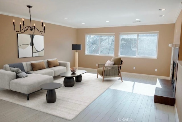 living area featuring wood finished floors, baseboards, ornamental molding, and an inviting chandelier