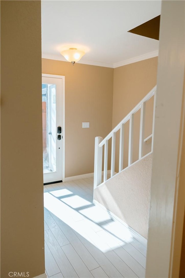 entrance foyer with wood finished floors, crown molding, and baseboards