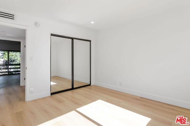 unfurnished bedroom featuring hardwood / wood-style floors and a closet