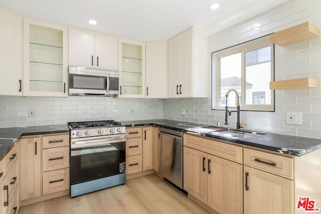 kitchen featuring tasteful backsplash, stainless steel appliances, light hardwood / wood-style floors, and sink