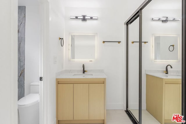 bathroom featuring vanity, toilet, and a shower with door