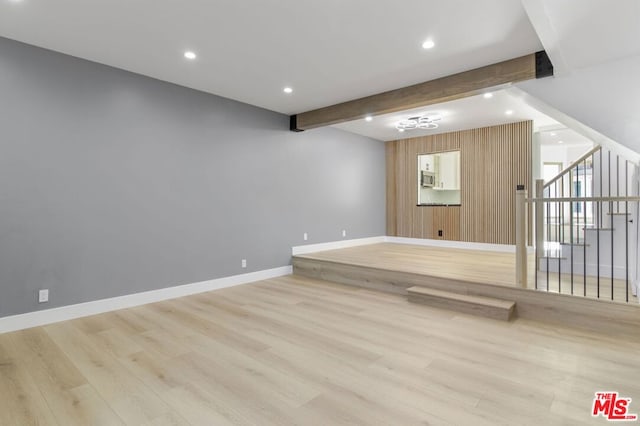 interior space featuring wooden walls, beam ceiling, and light hardwood / wood-style flooring