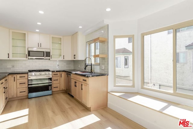 kitchen featuring sink, light hardwood / wood-style flooring, stainless steel appliances, light brown cabinetry, and decorative backsplash