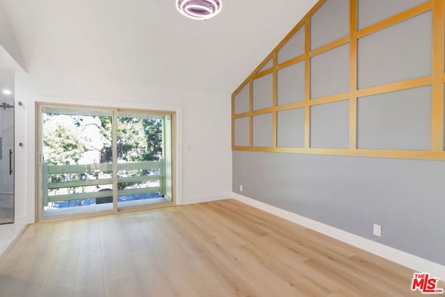 spare room featuring wood-type flooring and high vaulted ceiling