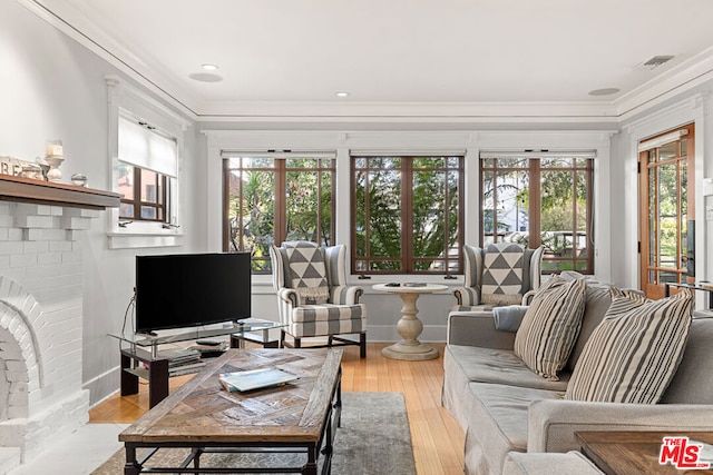 living room featuring crown molding, light wood-type flooring, and a fireplace