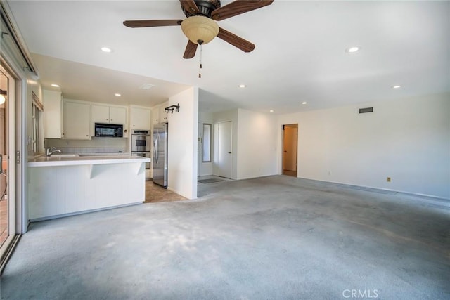 kitchen featuring a kitchen breakfast bar, kitchen peninsula, ceiling fan, stainless steel appliances, and white cabinets