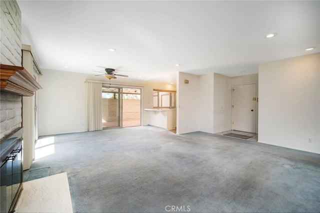 unfurnished living room featuring ceiling fan and a large fireplace