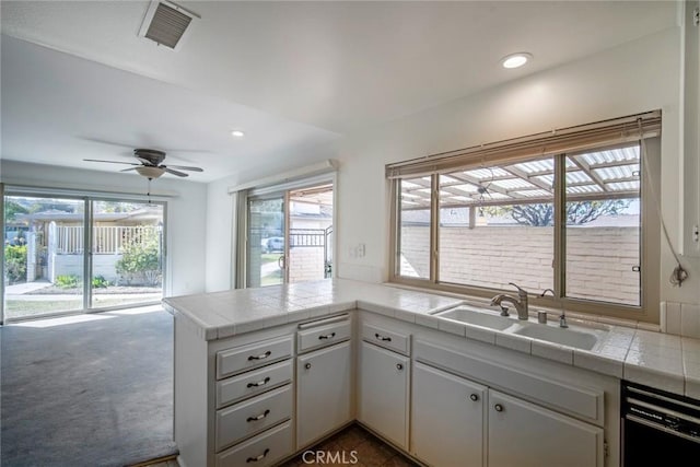 kitchen featuring sink, white cabinetry, tile counters, black dishwasher, and kitchen peninsula