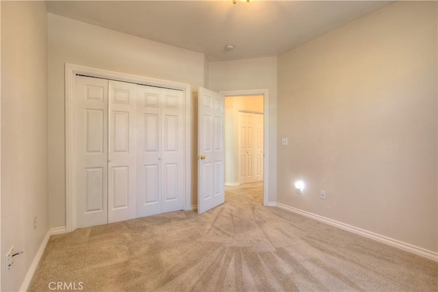 unfurnished bedroom with light colored carpet and a closet