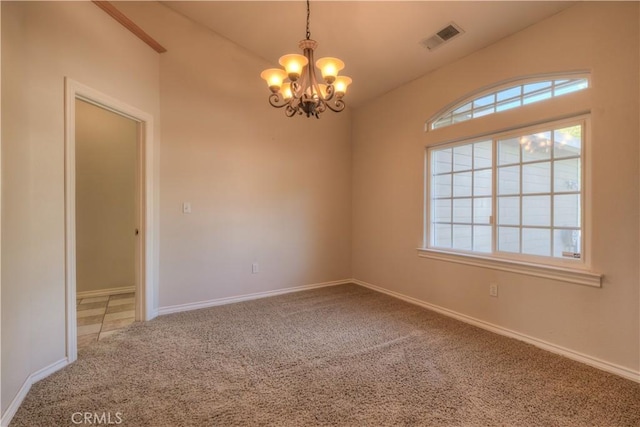 carpeted empty room featuring a notable chandelier