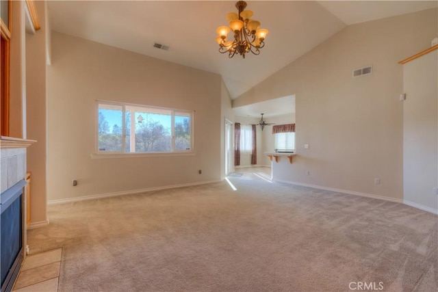 unfurnished living room featuring light colored carpet, a tiled fireplace, high vaulted ceiling, and a notable chandelier