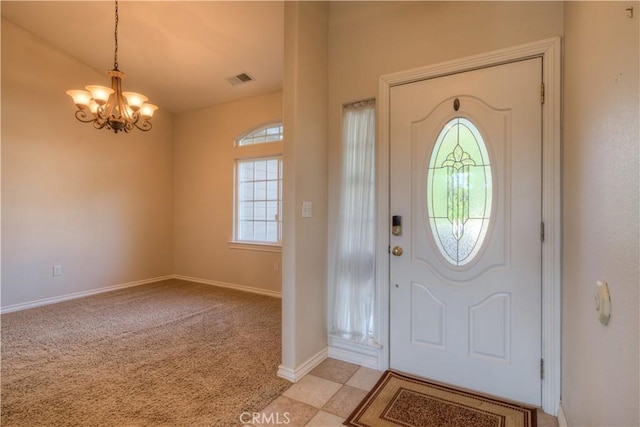 carpeted foyer featuring a wealth of natural light and a notable chandelier