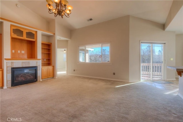 unfurnished living room with light colored carpet, vaulted ceiling, a tile fireplace, and a notable chandelier