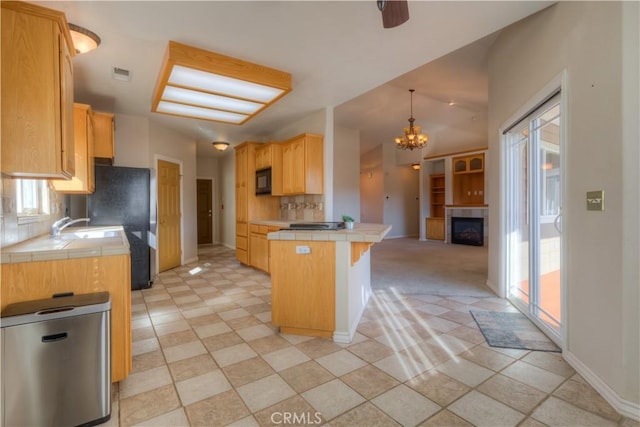 kitchen with a breakfast bar area, hanging light fixtures, tasteful backsplash, tile counters, and light brown cabinets