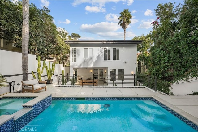 rear view of property with a swimming pool with hot tub and a patio area