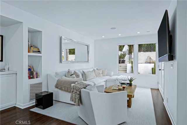 living room with dark hardwood / wood-style flooring and built in shelves