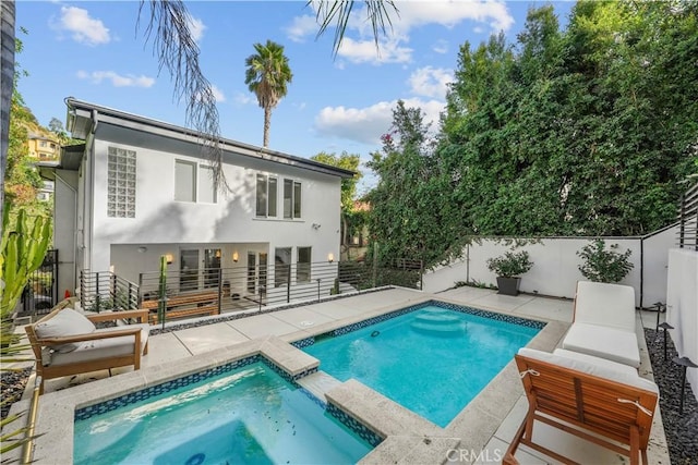 rear view of house featuring an in ground hot tub and a patio