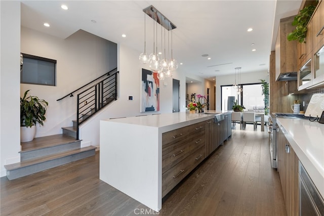 kitchen with pendant lighting, stainless steel stove, dark hardwood / wood-style floors, and a spacious island