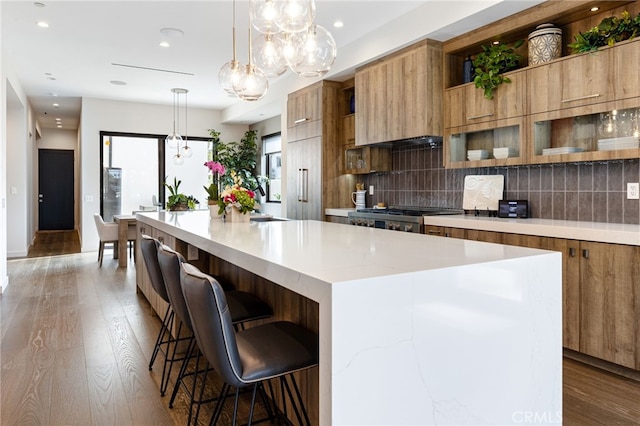 kitchen featuring a kitchen island, a breakfast bar, decorative light fixtures, tasteful backsplash, and range