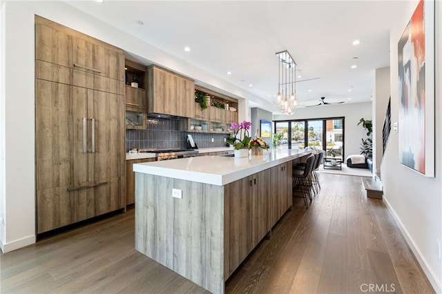 kitchen featuring tasteful backsplash, a breakfast bar area, a large island, and hanging light fixtures