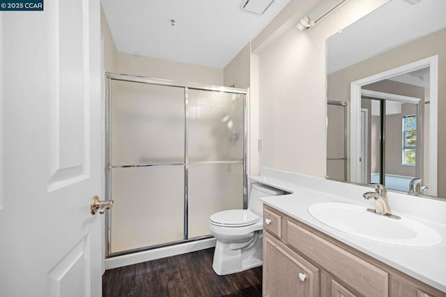 bathroom with hardwood / wood-style flooring, vanity, toilet, and a shower with shower door